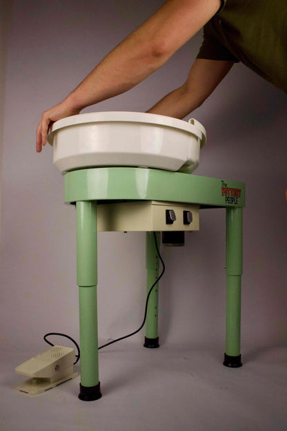 person adjusting splashpan on home studio potery wheel